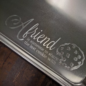 May include: A silver baking sheet with the text "A friend is someone to share the last cookie with" engraved on it. A cookie outline is also engraved on the sheet.
