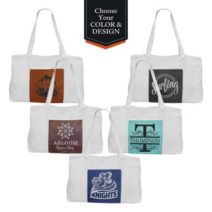 May include: Five white canvas tote bags with different designs. The designs include a mountain range, a flower, a monogram, a surfer, and a knight.  Choose your color and design.