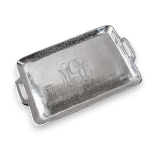 May include: A silver serving tray with two handles and a monogrammed design. The monogram is "MGL" in a script font.