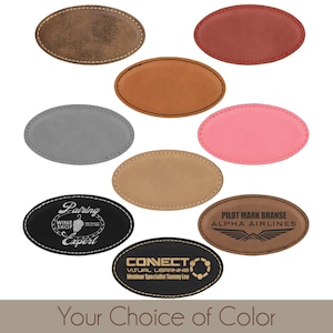 May include: Ten oval-shaped leather name tags in various colors, including brown, red, gray, pink, and black. The name tags have a stitched border and are blank except for two that have personalized text.