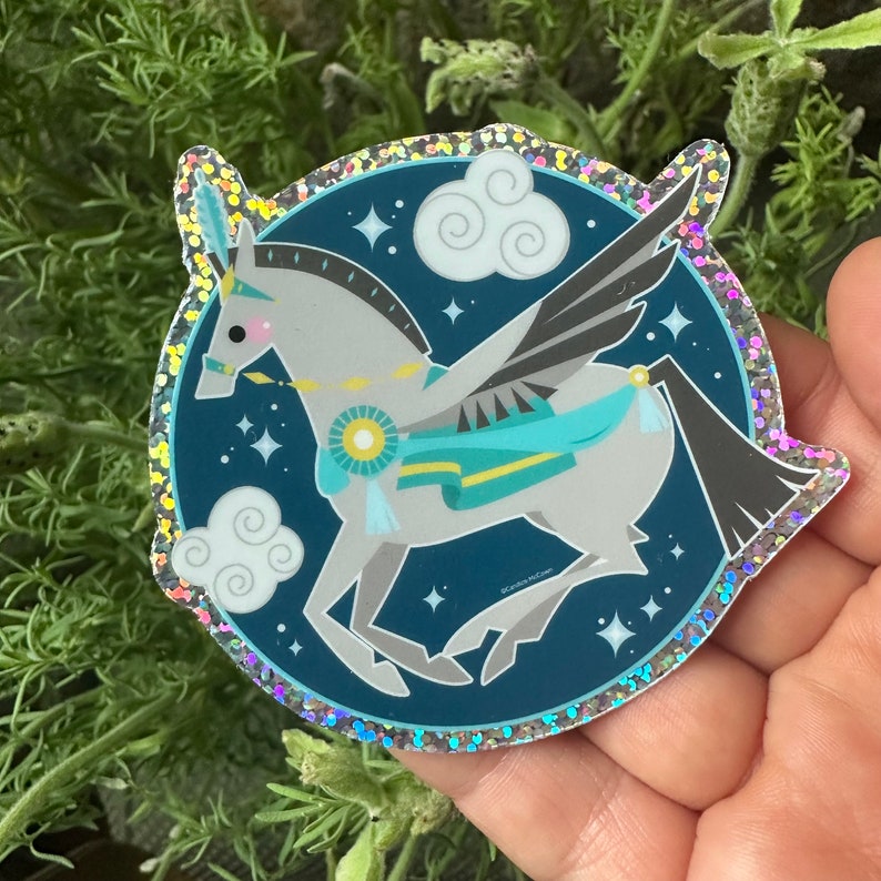 Puede incluir: Una pegatina brillante con un caballo alado blanco con una silla de montar azul y verde, volando sobre un fondo azul oscuro con nubes blancas y estrellas.