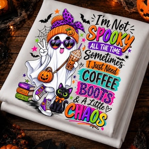 May include: A white t-shirt featuring a cartoon ghost wearing a purple leopard print beanie and heart-shaped sunglasses, holding a coffee cup and making a peace sign. Beside the ghost is a black cat, books, and text reading I'm Not SPOOKY ALL THE TIME SOMETIMES I Just Need COFFEE BOOTS & A Little CHAOS.