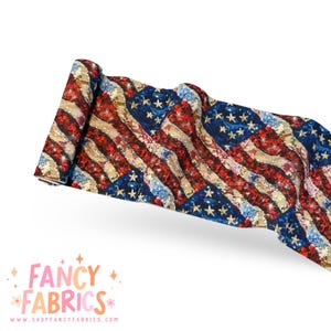 Può includere: Tessuto arrotolato con un design a bandiera americana invecchiata. Il tessuto mostra strisce rosse e bianche e un campo blu di stelle. L'immagine include il testo "FANCY FABRICS" e un indirizzo web.