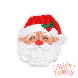 May include: An embroidered patch featuring the face of Santa Claus with a red hat, white fur trim, a green holly leaf with a red berry, a peach-colored face, and a thick white beard. The text FANCY FABRICS is printed in the bottom right corner.