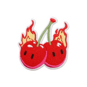 May include: An embroidered patch featuring two red cherries with white highlights and black rectangular eyes. Each cherry is engulfed in yellow and orange flames, and they are connected by two green stems that meet at the top.