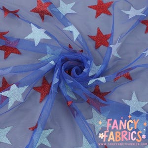 May include: Blue fabric with red and light blue glittery star patterns. The fabric is gathered in the center, creating a swirling effect. The words "FANCY FABRICS" are printed in pink and white in the lower right corner.