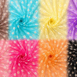 May include: A collection of eight swatches of sheer tulle fabric arranged in a grid, each featuring a repeating pattern of small white daisy flowers with yellow centers. The colors include brown, turquoise, yellow, purple, pink, magenta, orange, and black.