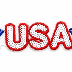 May include: A headband featuring the letters "USA" in red and white sequins, with a red stitched border. Two blue sequined stars are on either side of the text, creating a patriotic design.