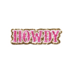 Puede incluir: Un parche bordado rectangular que presenta la palabra HOWDY en hilo rosa brillante con un borde blanco. El fondo del parche está cubierto con una textura de purpurina dorada brillante, creando un contraste marcado con las letras rosas.