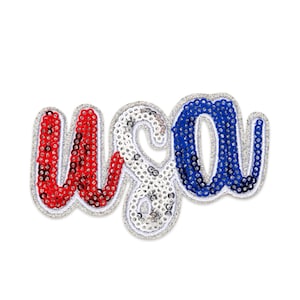 May include: A sequined patch spelling out "USA" in red, white, and blue. The letters are outlined in silver glitter, with the red and blue letters filled with sequins. The white letter is filled with white sequins.