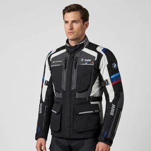 Könnte beinhalten: Eine schwarz-grau-weiße Motorradjacke mit BMW-Logo auf Brust und Ärmel sowie blauen und roten Zierstreifen am Arm. Die Jacke verfügt über mehrere Reißverschlusstaschen, einen Stehkragen und verstellbare Riemen an der Taille.