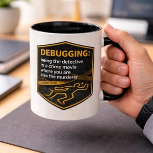 May include: White coffee mug with a black interior and handle. The mug features a yellow and black graphic with the text "DEBUGGING: being the detective in a crime movie where you are also the murderer." A crime scene outline is also included.