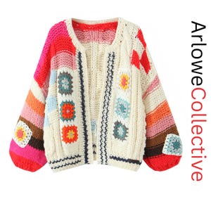 Könnte beinhalten: Eine grob gestrickte Strickjacke mit cremefarbener Basis, bunten Granny-Square-Aufnähern und gestreiften Ärmeln in Rosa, Orange, Rot und Braun. Die Vorderkanten haben eine dunkelblaue Verzierung und der Text ArloweCollective ist zu sehen.