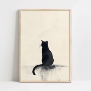 May include: A framed art print showing a black cat silhouette. The cat is seen from behind, with a long tail and whiskers. The background is a light beige, and the frame is a light wood colour.