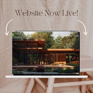 Op de afbeelding: Een laptop toont een website met een modern architectonisch ontwerp. Het scherm toont een huis met grote ramen en een houten buitenkant. De tekst "Website Now Live!" staat boven de laptop, met gebogen pijlen die naar het scherm wijzen.