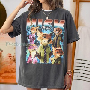 Pode incluir: T-shirt cinza escuro com um gr&aacute;fico de Nick Wilde de Zootopia. O design inclui v&aacute;rias imagens do personagem em v&aacute;rias roupas, com o nome "Nick Wilde" em uma fonte estilizada. A camisa tem um visual vintage e desgastado.
