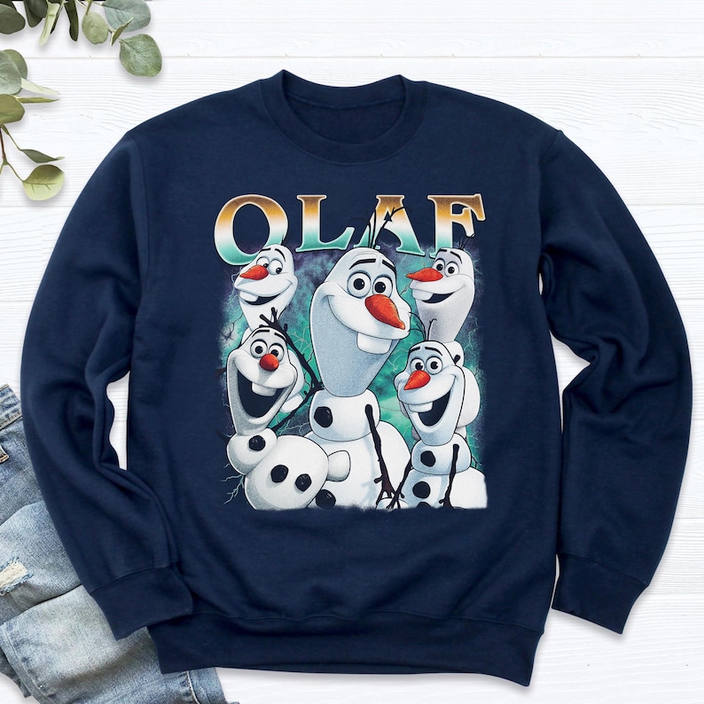 Puede incluir: Sudadera azul marino con un dise&ntilde;o de Olaf de Frozen. El dise&ntilde;o incluye m&uacute;ltiples personajes de Olaf con narices de zanahoria y la palabra "OLAF" en una fuente degradada. La sudadera est&aacute; hecha de un material suave.