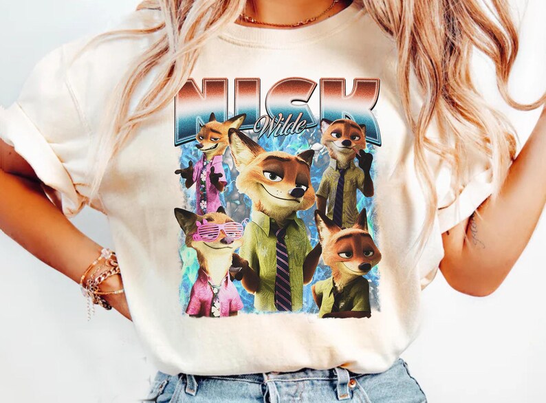 Pode incluir: Camiseta creme com um gr&aacute;fico de Nick Wilde de Zootopia. O design inclui v&aacute;rias imagens de Nick em v&aacute;rias roupas, com o nome "Nick Wilde" em uma fonte retr&ocirc;. A camiseta &eacute; uma pe&ccedil;a de roupa casual.