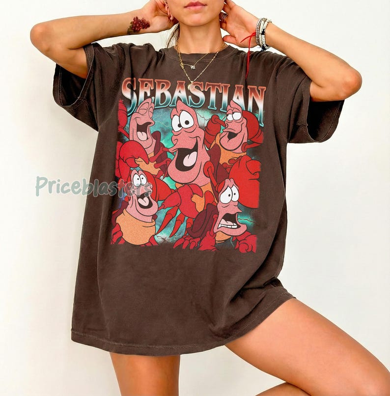 Pu&ograve; includere: T-shirt marrone con una grafica di Sebastian il granchio e altri personaggi de La Sirenetta. La parola "Sebastian" &egrave; stampata in alto con un carattere colorato. La maglietta ha maniche corte e una vestibilit&agrave; ampia.