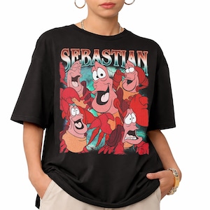 Pu&ograve; includere: T-shirt nera con una grafica di Sebastian il granchio de La Sirenetta. Il design include la parola "Sebastian" in un font retr&ograve; e diversi granchi dei cartoni animati. La maglietta &egrave; un classico girocollo.