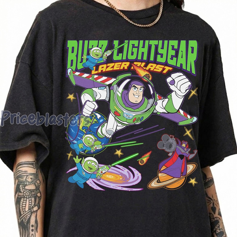 May include: Black t-shirt featuring a colorful graphic of Buzz Lightyear in flight, with the words "Buzz Lightyear Lazer Blast" in green. The design includes space aliens and a villain.