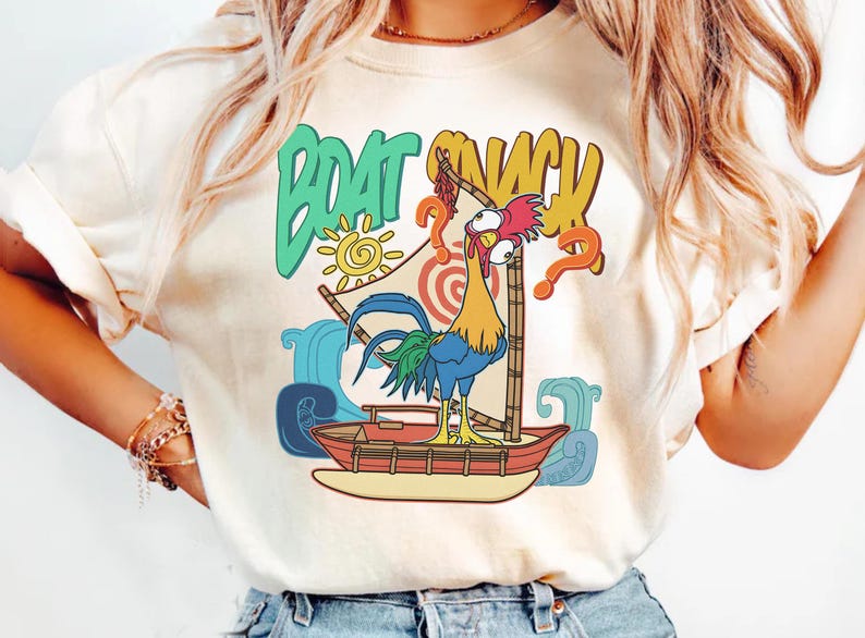 Puede incluir: Camiseta color crema con un gallo de dibujos animados en un barco con las palabras "BOAT SNACK". El dise&ntilde;o incluye un sol, olas y signos de interrogaci&oacute;n, creando un ambiente tropical divertido. El gallo es colorido, con plumas azules, amarillas y rojas.