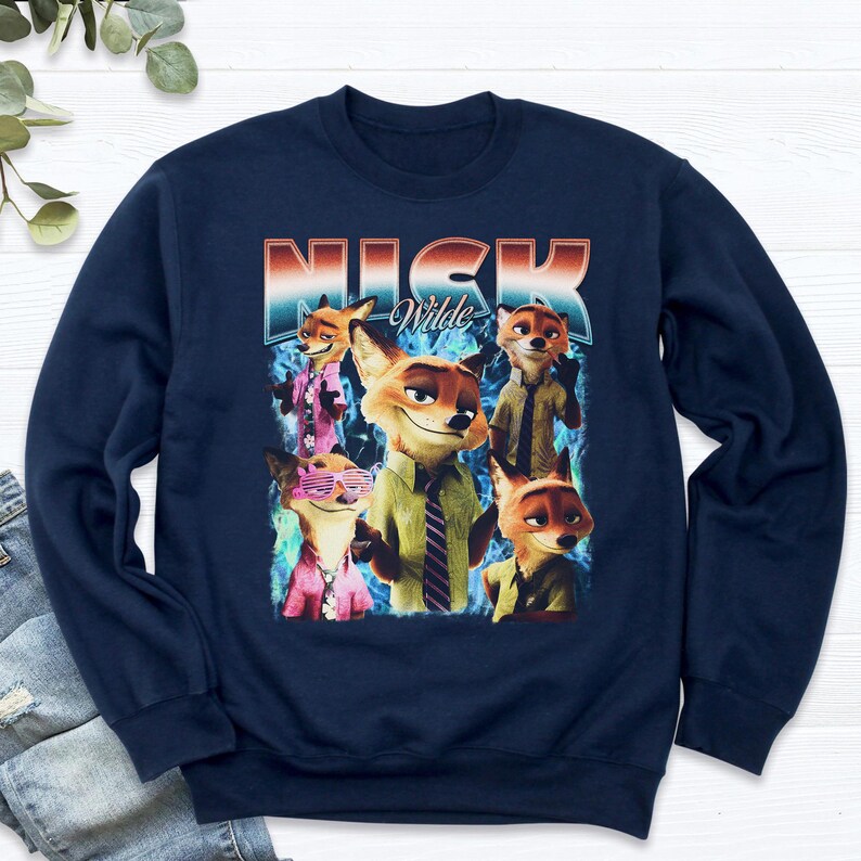 Pode incluir: Camisola azul marinho com um gr&aacute;fico de Nick Wilde de Zootopia. O design inclui v&aacute;rias imagens de Nick Wilde com o texto "Nick Wilde" em uma fonte retr&ocirc;. A camisola &eacute; um estilo casual e confort&aacute;vel.