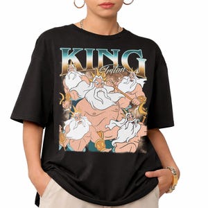 May include: Black t-shirt featuring a graphic of King Triton with the text "KING Triton" in a vintage style. The illustration depicts King Triton with a white beard and a golden crown. The shirt is a short-sleeved, casual style.