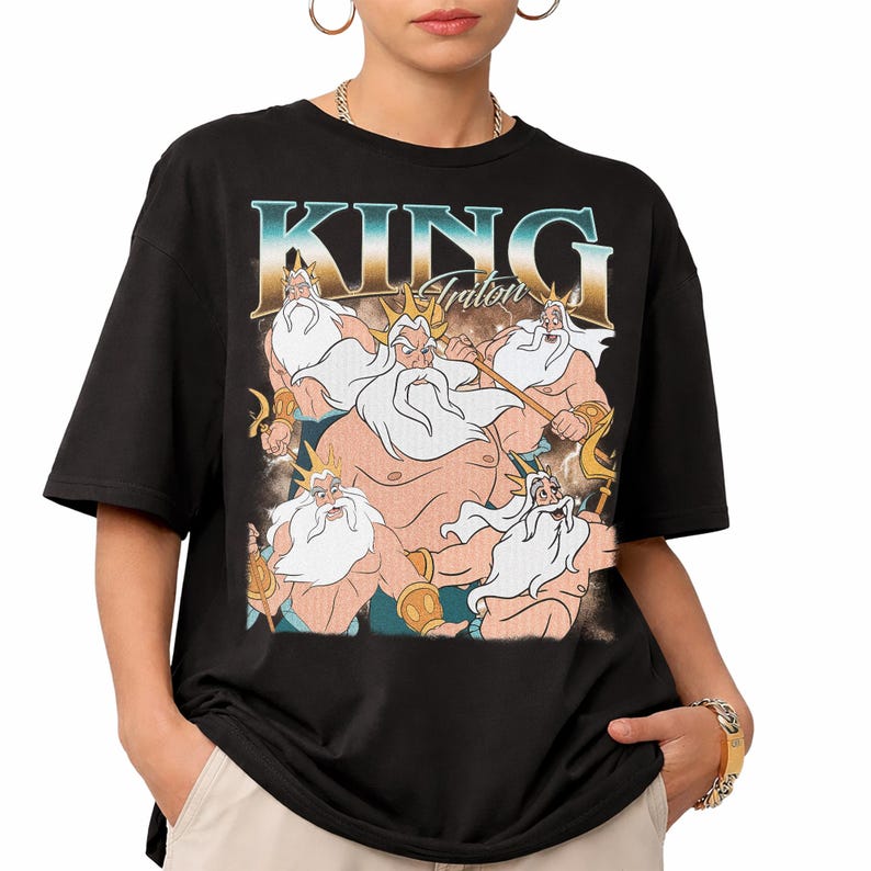 May include: Black t-shirt featuring a graphic of King Triton with the text "KING Triton" in a vintage style. The illustration depicts King Triton with a white beard and a golden crown. The shirt is a short-sleeved, casual style.