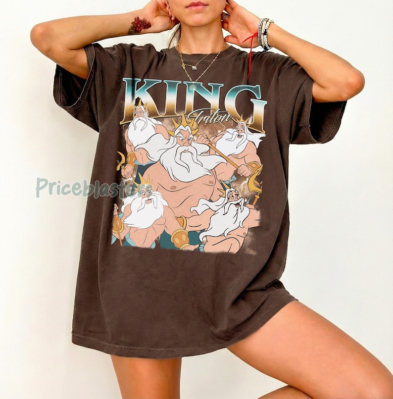 May include: Brown t-shirt featuring a graphic of King Triton from The Little Mermaid. The design includes the text "KING Triton" in a blue and gold font, with an illustration of the character and other figures.