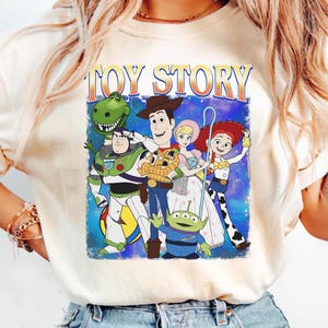 Puede incluir: Camiseta color crema con un gr&aacute;fico de personajes de la pel&iacute;cula animada "Toy Story". El dise&ntilde;o incluye a Woody, Buzz Lightyear, Jessie, Rex, Bo Peep y los Little Green Men, con las palabras "Toy Story" arriba.