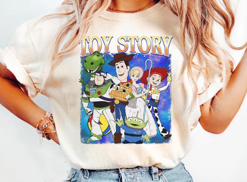 Puede incluir: Camiseta color crema con un gr&aacute;fico de personajes de la pel&iacute;cula animada "Toy Story". El dise&ntilde;o incluye a Woody, Buzz Lightyear, Jessie, Rex, Bo Peep y los Little Green Men, con las palabras "Toy Story" arriba.