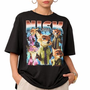 Pode incluir: Camiseta preta com um gr&aacute;fico de Nick Wilde de Zootopia. O design inclui v&aacute;rias imagens do personagem em v&aacute;rias roupas, com o nome "NICK Wilde" em uma fonte retr&ocirc;. O fundo tem um efeito esfuma&ccedil;ado azul e branco.