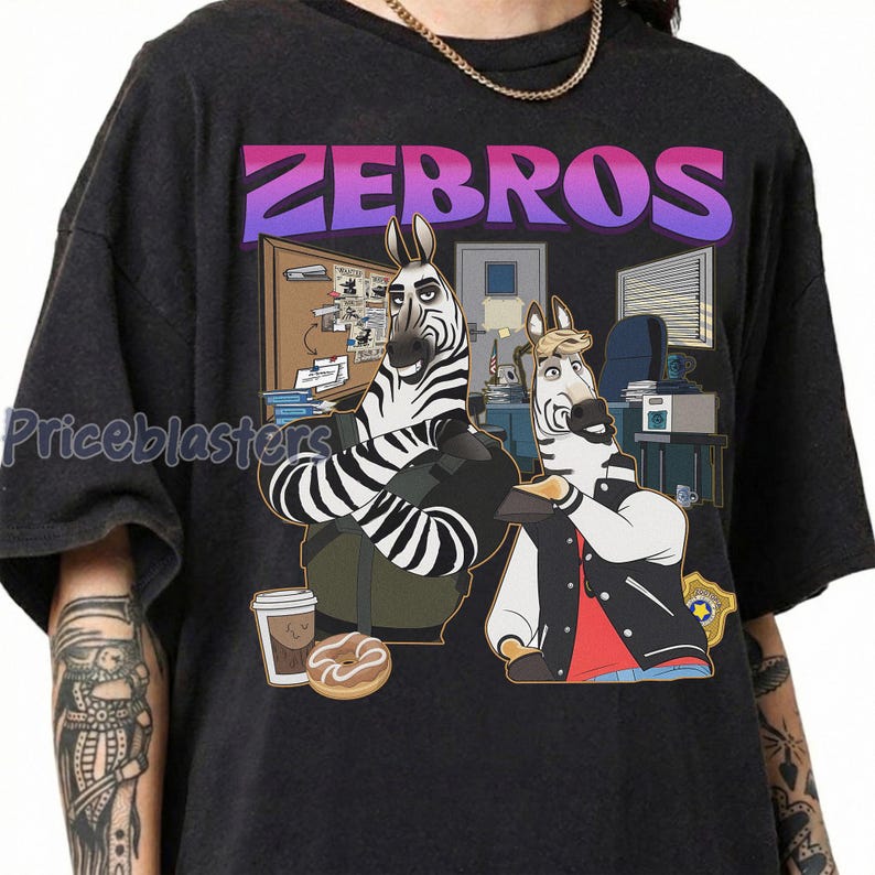 Pu&ograve; includere: T-shirt grigio scuro con un'illustrazione a cartoni animati di due zebre in un ufficio. Il testo "ZEBROS" &egrave; visualizzato sopra le zebre in una sfumatura di colore viola e rosa. Una zebra indossa una giacca e l'altra un gilet.