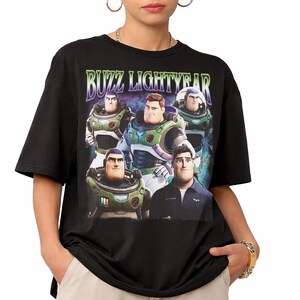 May include: Black t-shirt featuring a graphic of Buzz Lightyear and the text "BUZZ LIGHTYEAR" in a green and purple font. The graphic shows multiple images of Buzz Lightyear in different poses. The shirt is a crew neck and has short sleeves.
