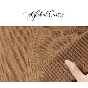 May include: Close-up of a brown waffle-knit fabric. The texture of the fabric is visible, with a grid-like pattern. The fabric is being touched by a person's finger. The top of the image has the text "eGlobal Cart".