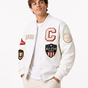 May include: A white varsity jacket featuring a large letter C patch, an All-Star League shield patch, a 1996 embroidery, a trophy emblem, and a basketball patch on the sleeve. The jacket has a snap-button front closure and ribbed cuffs.