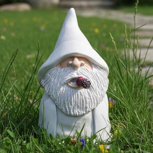 May include: A white garden gnome with a long white beard and a pointed hat, smoking a cigar. The gnome is set in a grassy garden with a stone pathway and flowers in the background. A whimsical outdoor decoration.