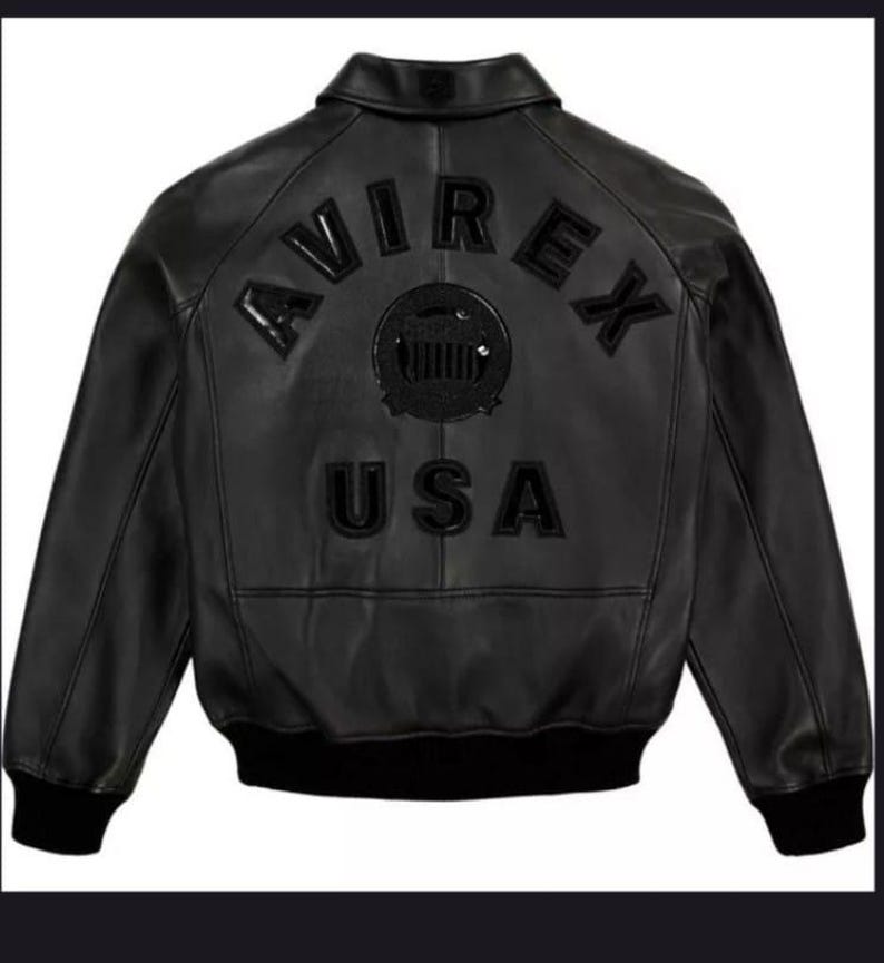 May include: Black leather bomber jacket with the word "AVIREX" arched across the upper back, above a circular emblem and the word "USA". The jacket has a ribbed collar, cuffs, and hem. The jacket is a classic style.