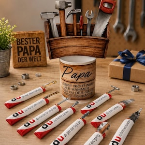 May include: A wooden toolbox filled with various tools, including hammers and a saw. Below, several red and white handled tools are arranged on a wooden surface. A small wooden block reads "BESTER PAPA DER WELT".