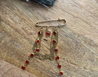 Broche dorado “Glamour del Vino” – Diamantes de imitación rojos y cadenas colgantes