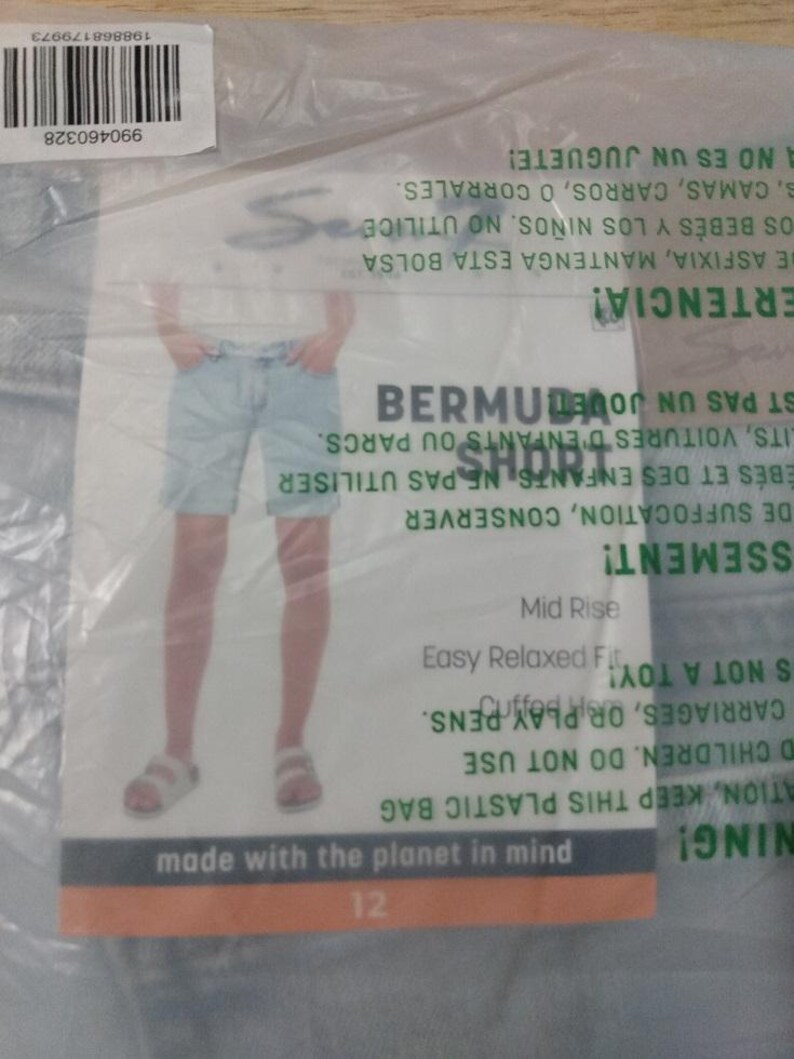 May include: Light blue denim Bermuda shorts in a clear plastic bag. The packaging features a product image, the text BERMUDA SHORT, Mid Rise, Easy Relaxed Fit, Cuffed Hem, and made with the planet in mind, along with a barcode and safety warnings.