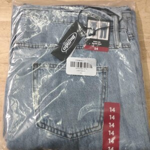 May include: Light wash blue denim jeans in a wide leg style with a belt, enclosed in a clear plastic bag. The jeans feature a Buffalo brand tag, a barcode label with the text ITEM# 9904, and a red vertical strip displaying the size 14 repeatedly.