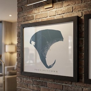 May include: A framed print of Provincetown, Massachusetts, in a teal color, with a detailed map design. The print is set against a white background and framed in a black wooden frame. The word "PROVINCETOWN" is printed in a serif font below the map.