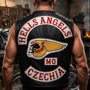 May include: A black leather vest featuring a large embroidered patch on the back. The patch displays the text HELLS ANGELS in red on a white arc, a winged skull emblem in yellow and red, the letters MG, and the word CZECHIA in red on a white arc.