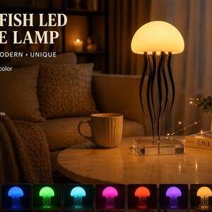 以下が含まれることがあります： クラゲ型のLEDテーブルランプ。柔らかく温かい光を発します。ランプは白く丸みを帯びた上部と、黒く流れる触手を持っています。7色のオプションがあり、USB電源です。画像には「JELLYFISH LED TABLE LAMP」と書かれています。