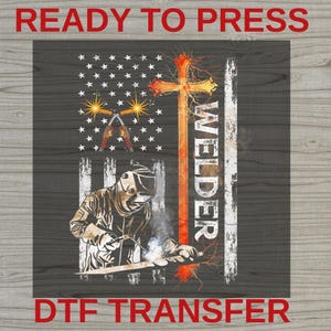 May include: A DTF transfer sheet featuring a graphic of a welder in protective gear, a large orange cross, and a stylized American flag background. The design includes the text "WELDER" vertically along the cross and "READY TO PRESS" at the top.