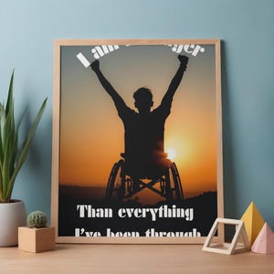Puede incluir: Un póster enmarcado con la silueta de una persona en silla de ruedas con los brazos levantados contra un atardecer. Incluye el texto "I am stronger than everything I've been through."