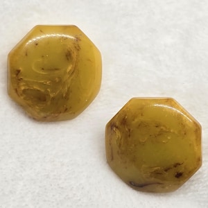 May include: Two octagonal buttons with a smooth, glossy finish. The buttons feature a marbled mustard yellow color with dark brown, vein-like streaks throughout the surface. Each button has eight distinct sides and a flat, uniform appearance.