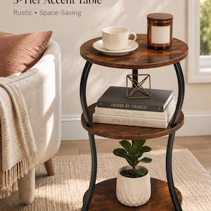 May include: A 3-tier accent table with three round, dark wood-grain shelves and curved black metal legs. The top shelf holds a white cup and saucer and a brown candle. The middle shelf holds three stacked books and a gold geometric wire sculpture.